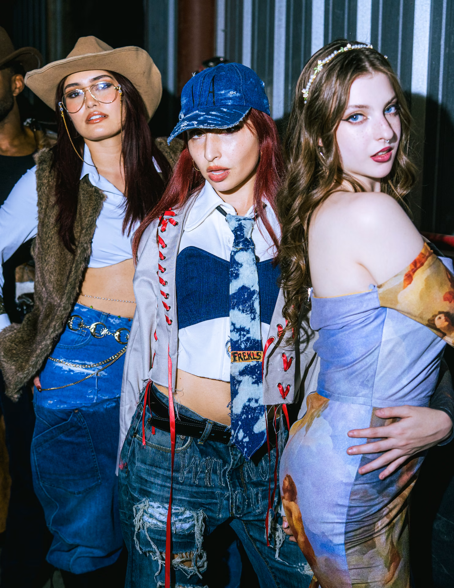 A pink off-shoulder mini and black cowboy boots cross a warehouse runway past a fallen Greek column; Texas swagger caught inside the live-show frame.