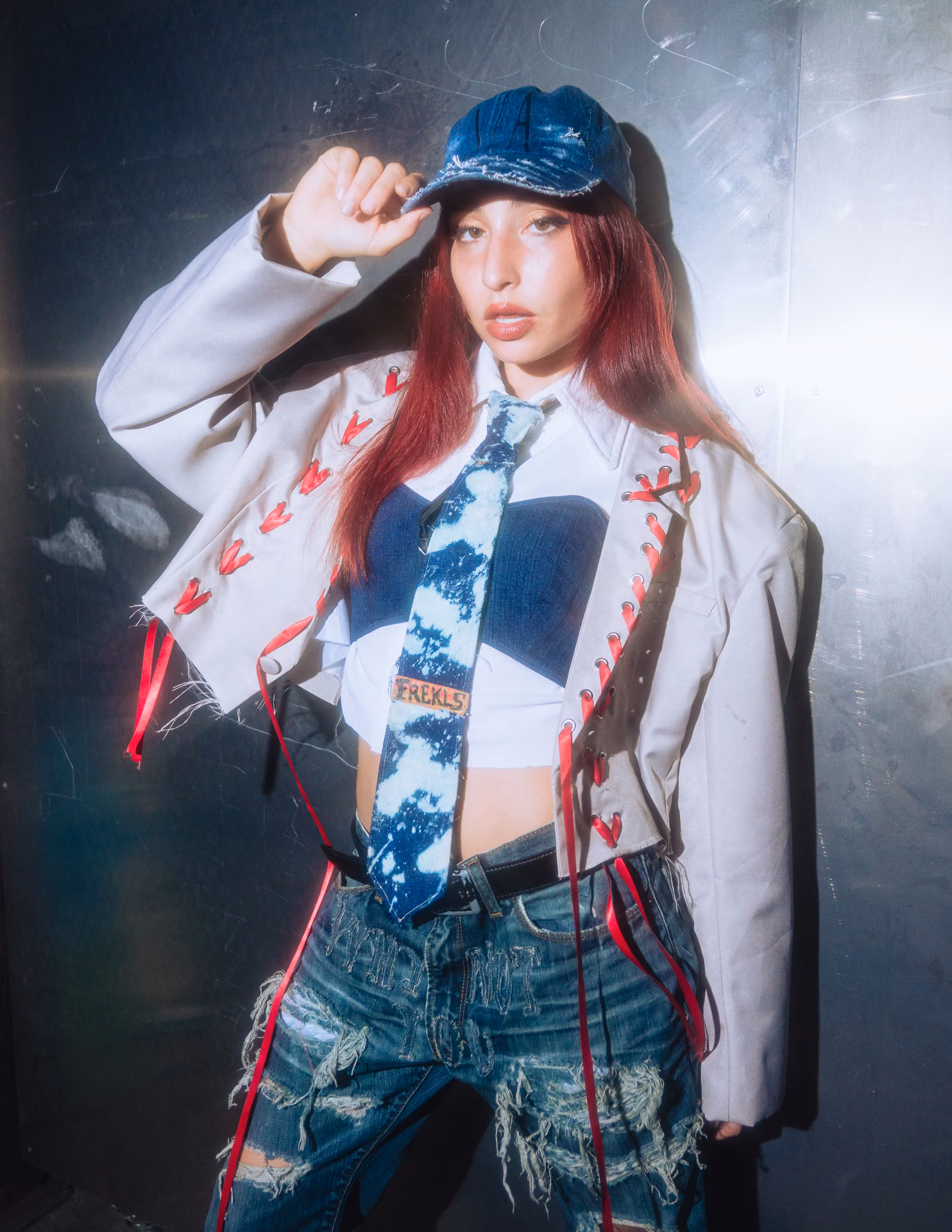 A pink off-shoulder mini and black cowboy boots cross a warehouse runway past a fallen Greek column; Texas swagger caught inside the live-show frame.